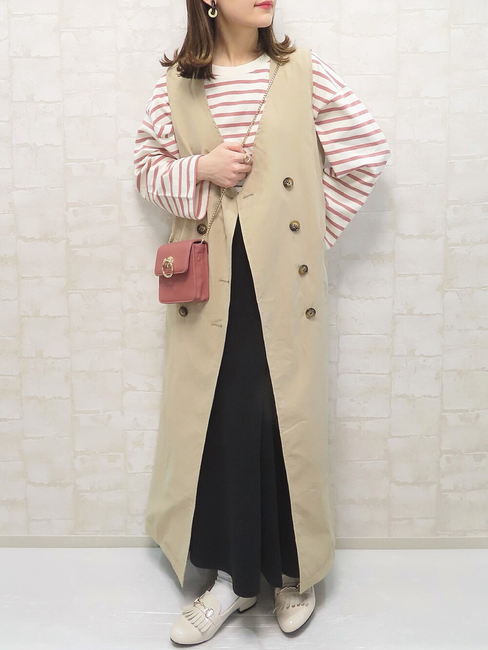 ベージュ系のトレンチコート、ピンク系のトップス、ピンク系のショルダーバッグを着用したレディースの春コーディネートの2枚目の写真
