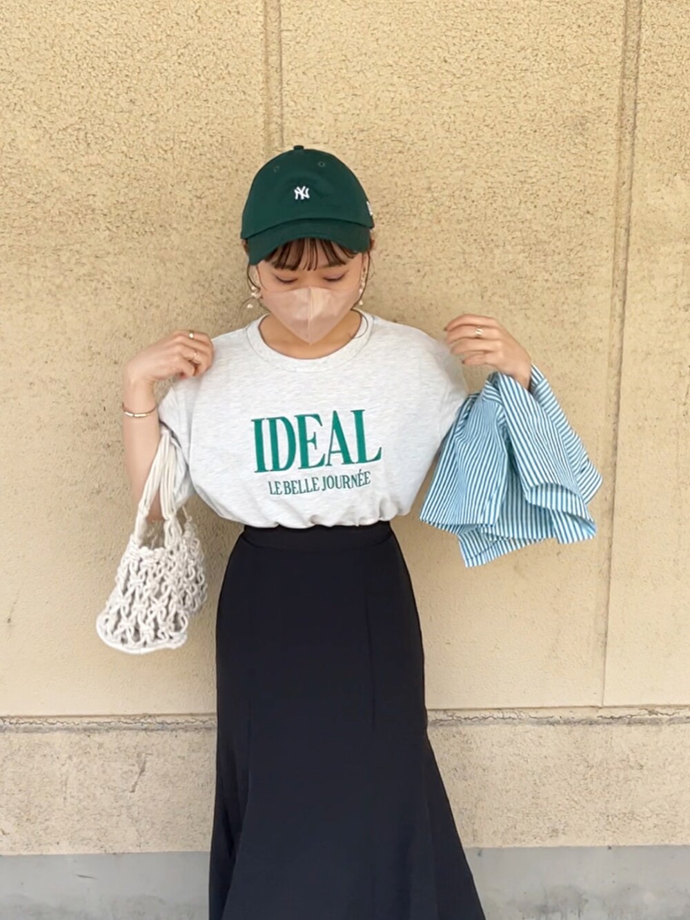 グリーン系のシャツ/ブラウス、ブラック系のスカート、ホワイト系のハンドバッグを着用したレディースの夏コーディネートの4枚目の写真