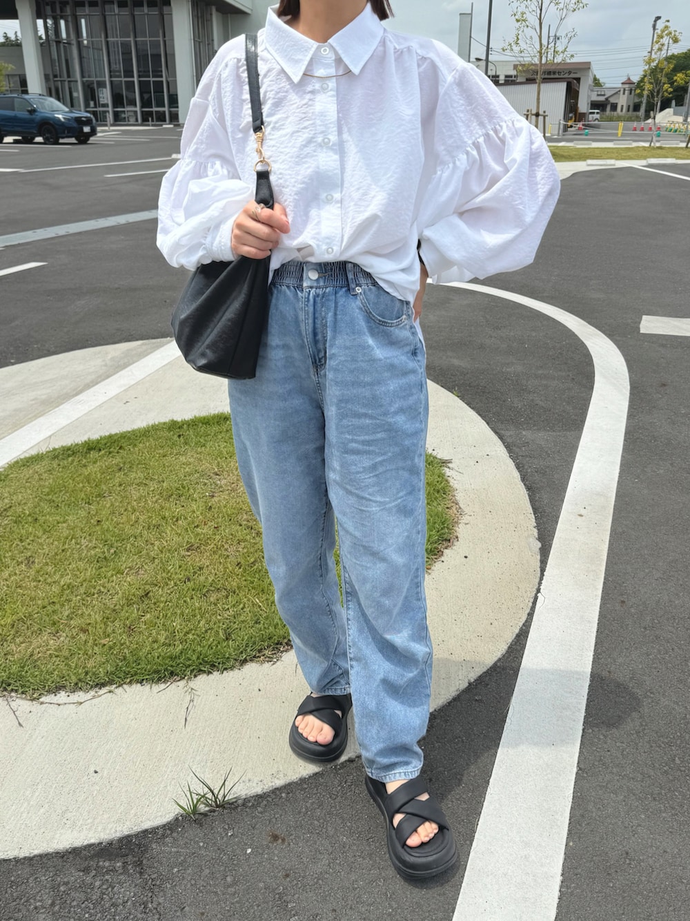 ホワイト系のシャツ/ブラウス、ブルー系のデニムパンツ、ブラック系のバッグを着用したレディースの秋コーディネートの2枚目の写真