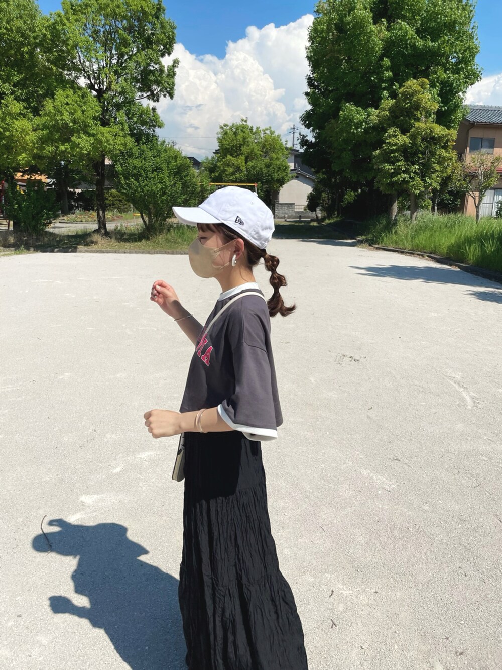 グレー系のTシャツ/カットソー、ブラック系のスカート、ホワイト系のキャップを着用したレディースの夏コーディネートの2枚目の写真