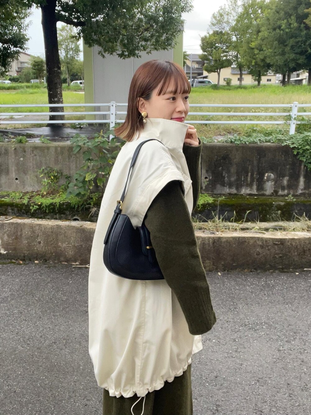 ホワイト系のミリタリージャケット、グリーン系のワンピース、ブラック系のバッグを着用したレディースの秋コーディネートの3枚目の写真