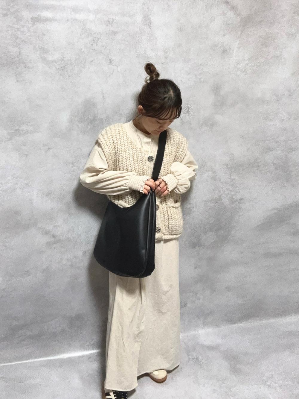 ベージュ系のシャツワンピース、ホワイト系のトップス、ブラック系のバッグを着用したレディースの冬コーディネートの2枚目の写真