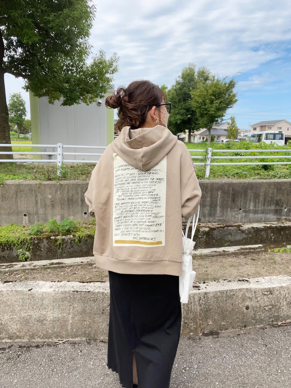 ベージュ系のパーカー、ブラック系のワンピース、ホワイト系のショルダーバッグを着用したレディースの夏コーディネートの2枚目の写真