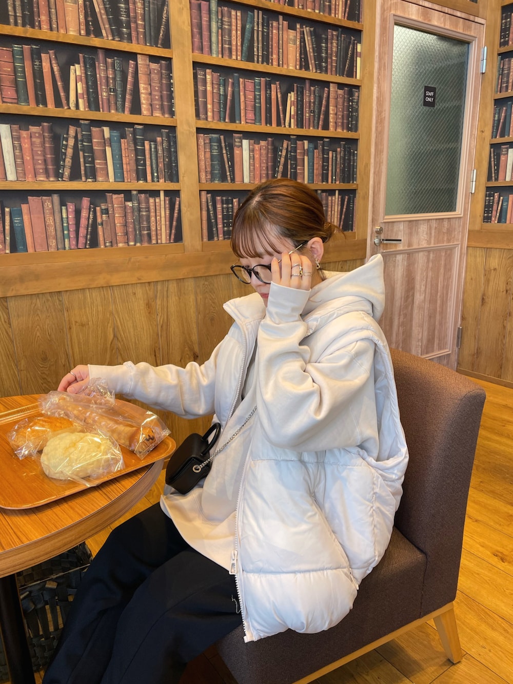 ホワイト系のパーカー、ホワイト系のベスト、ブラック系のショルダーバッグを着用したレディースの冬コーディネートの2枚目の写真