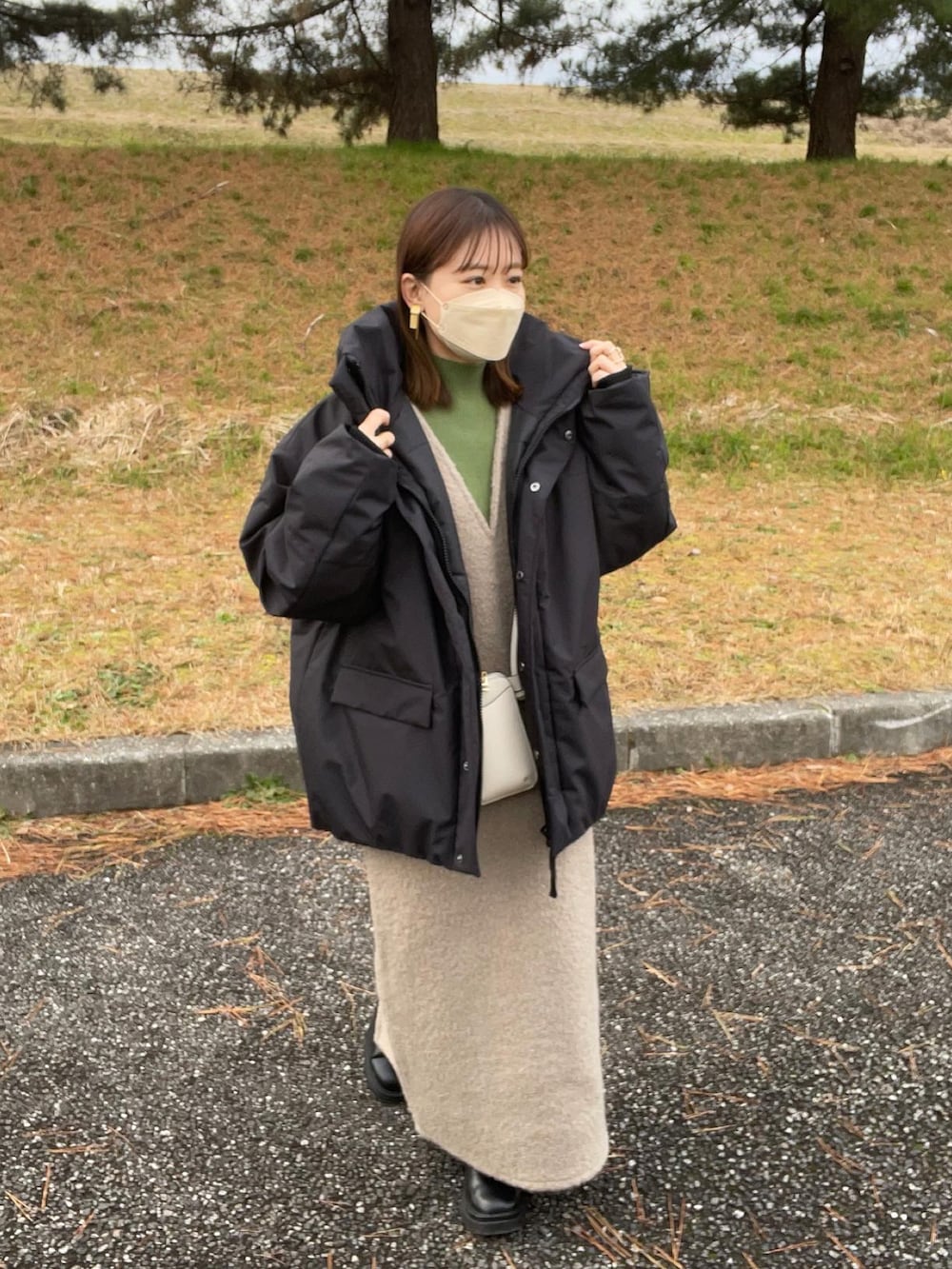 ブラック系のダウンジャケット/コート、グリーン系のニット/セーター、ブラウン系のワンピースを着用したレディースの冬コーディネートの3枚目の写真