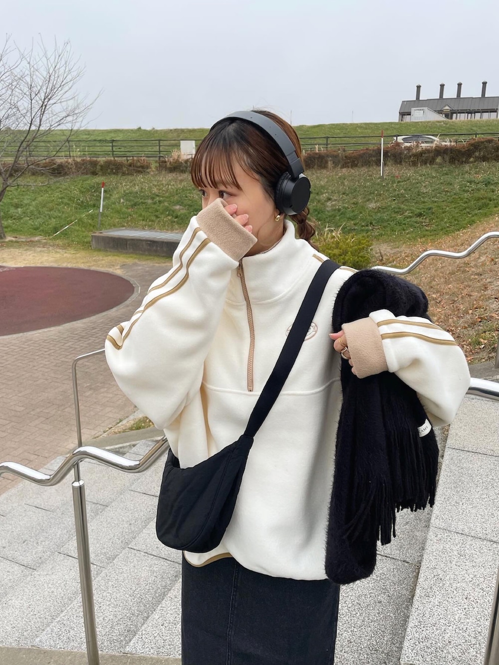 ブラック系のデニムスカート、ブラック系のショルダーバッグ、ホワイト系のスニーカーを着用したレディースの冬コーディネートの2枚目の写真