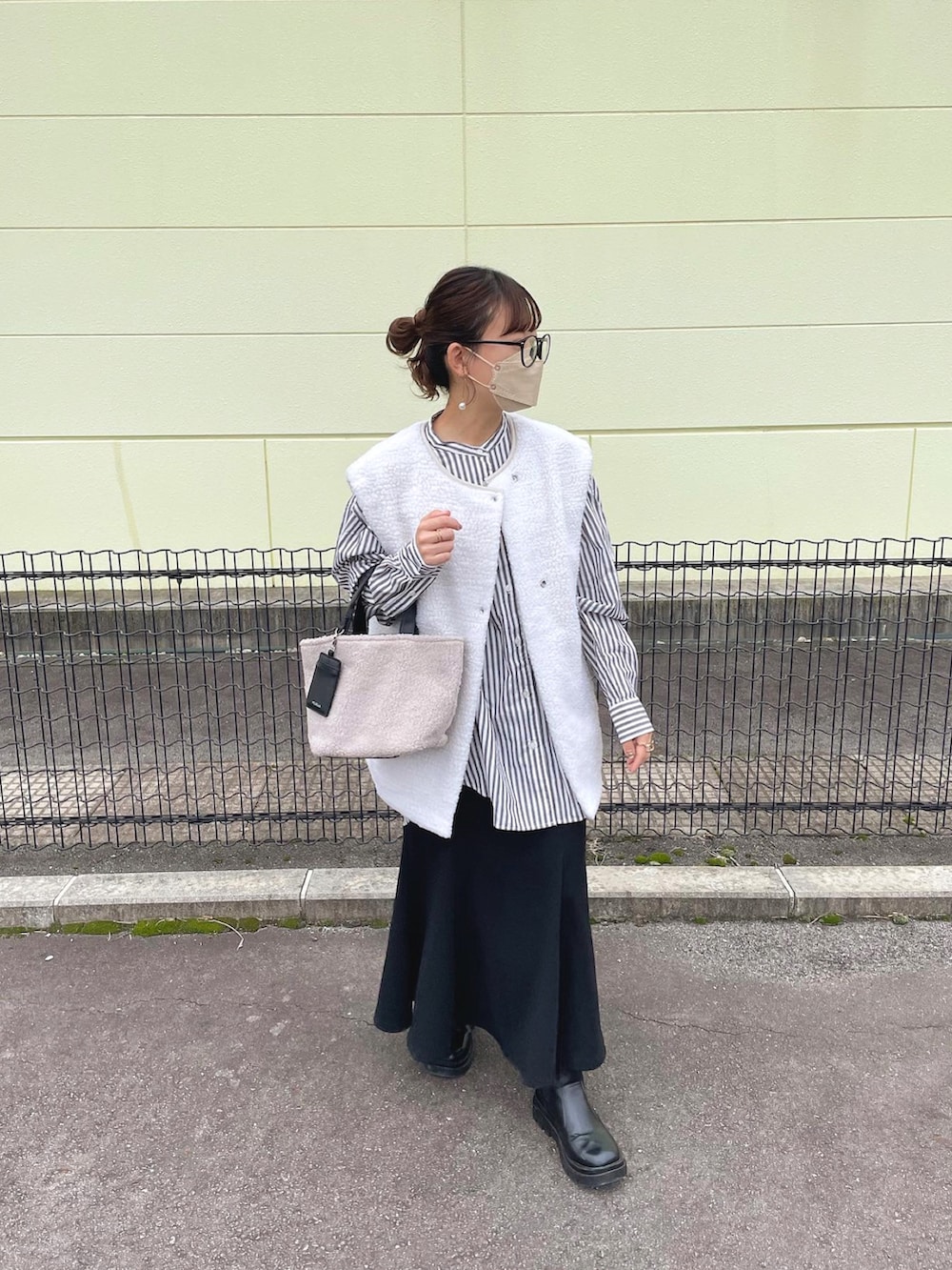 グレー系のトートバッグ、グレー系のシャツ/ブラウス、ホワイト系のベストを着用したレディースの秋コーディネートの3枚目の写真