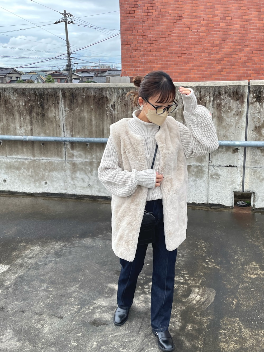 ベージュ系のニット/セーター、グレー系のベスト、ブラック系のデニムパンツを着用したレディースの秋コーディネートの4枚目の写真