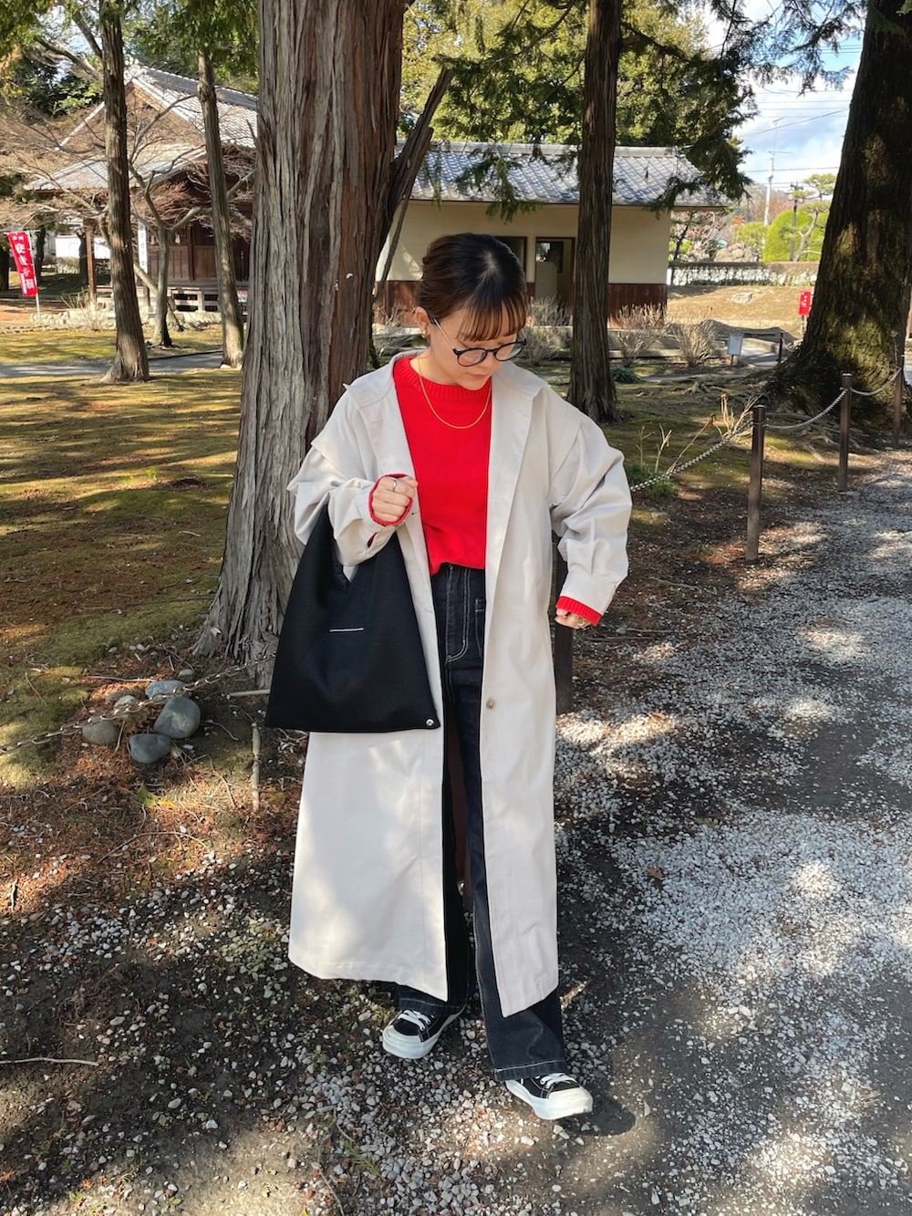 ベージュ系のトレンチコート、レッド系のニット/セーター、ブラック系のデニムパンツを着用したレディースの春コーディネートの2枚目の写真