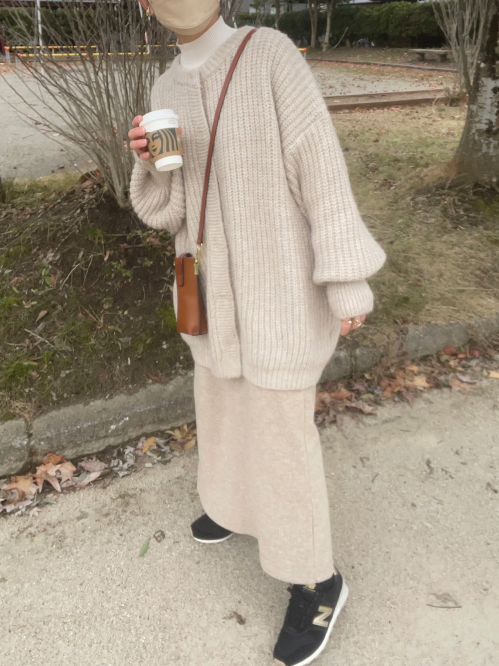 ホワイト系のカーディガン/ボレロ、ホワイト系のニット/セーター、ベージュ系のスカートを着用したレディースの冬コーディネートの5枚目の写真