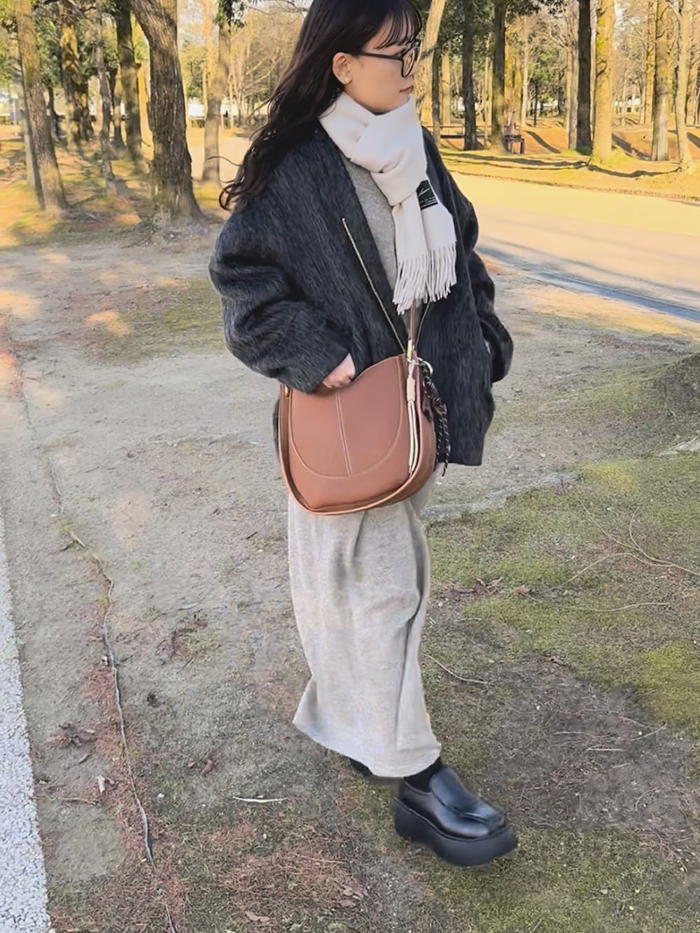 ブラック系のノーカラーコート、ベージュ系のワンピース、ブラック系のシューズを着用したレディースの冬コーディネートの4枚目の写真