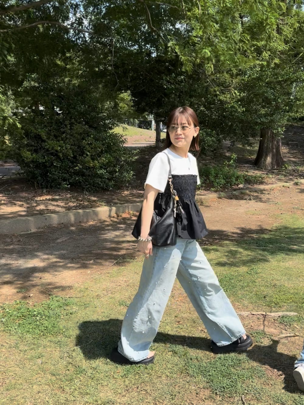 ホワイト系のTシャツ/カットソー、ブルー系のデニムパンツ、ブラック系のバッグを着用したレディースの夏コーディネートの3枚目の写真