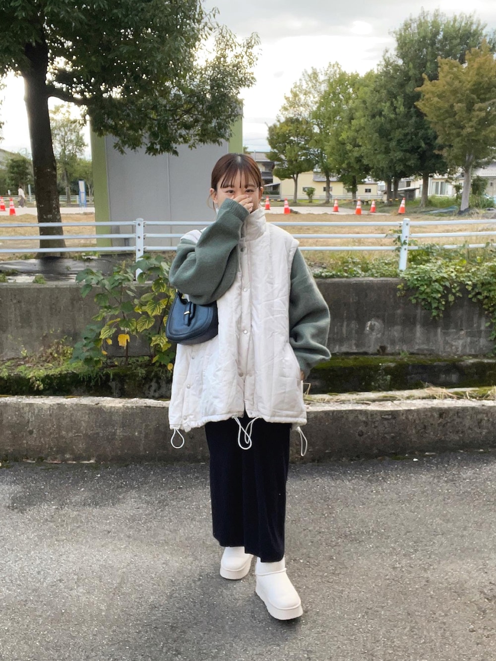 グリーン系のニット/セーター、ホワイト系のジャケット/アウター、ブラック系のバッグを着用したレディースの秋コーディネートの5枚目の写真