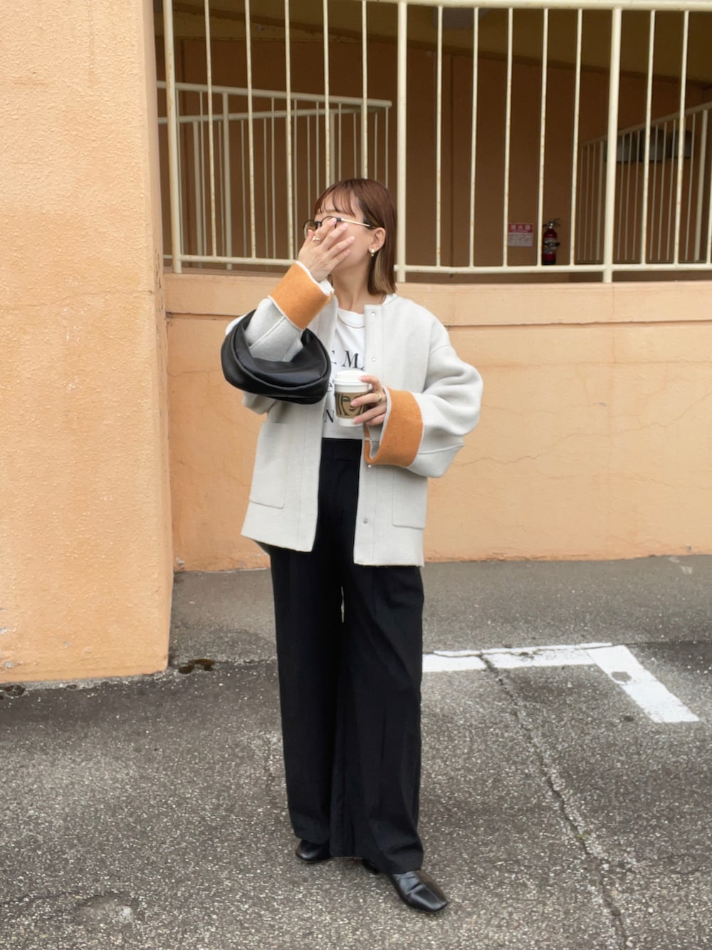 ベージュ系のノーカラーコート、ホワイト系のTシャツ/カットソー、ブラック系のパンツを着用したレディースの秋コーディネートの5枚目の写真