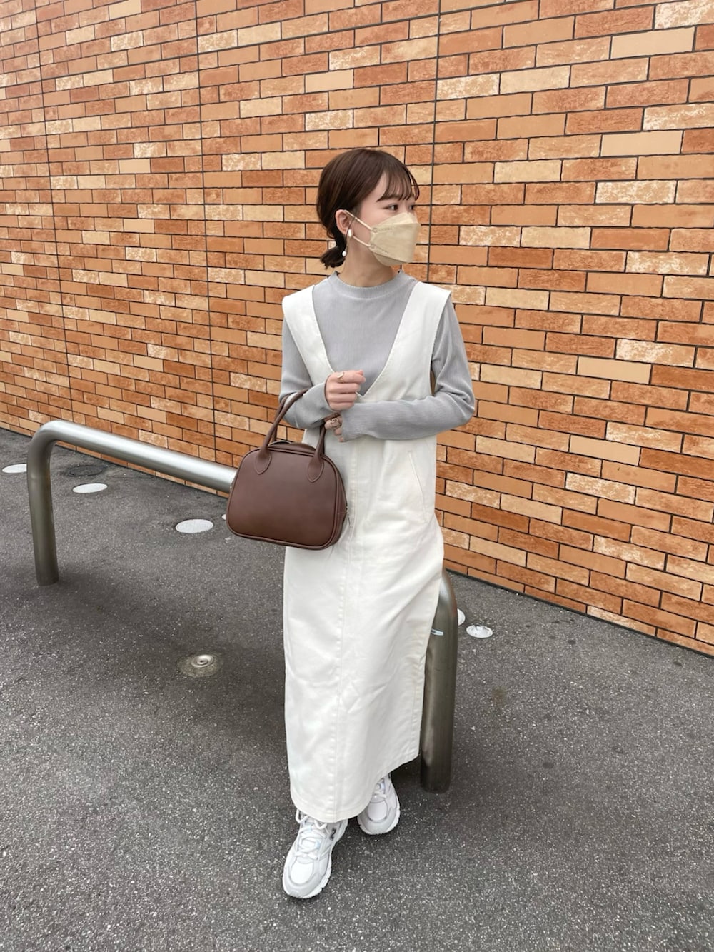 ベージュ系のTシャツ/カットソー、ホワイト系のジャンパースカート、ブラウン系のショルダーバッグを着用したレディースの春コーディネートの5枚目の写真