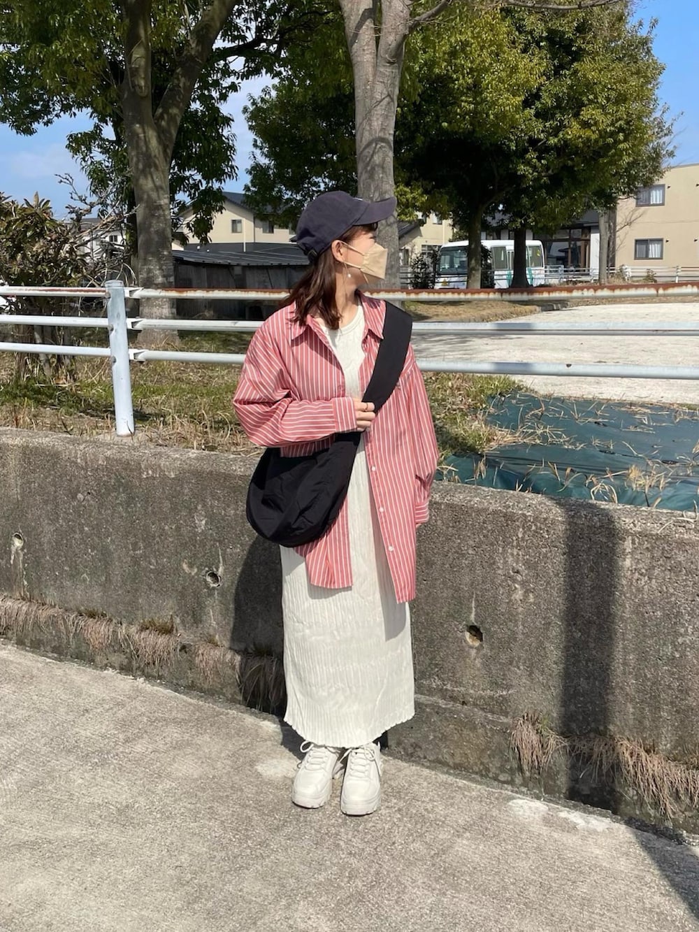 オレンジ系のシャツ/ブラウス、ホワイト系のワンピース、ブラック系のショルダーバッグを着用したレディースの春コーディネートの4枚目の写真