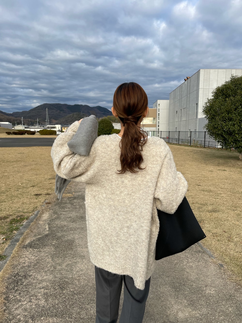 ベージュ系のカーディガン/ボレロ、グレー系のその他パンツ、ブラック系のトートバッグを着用したレディースの冬コーディネートの5枚目の写真