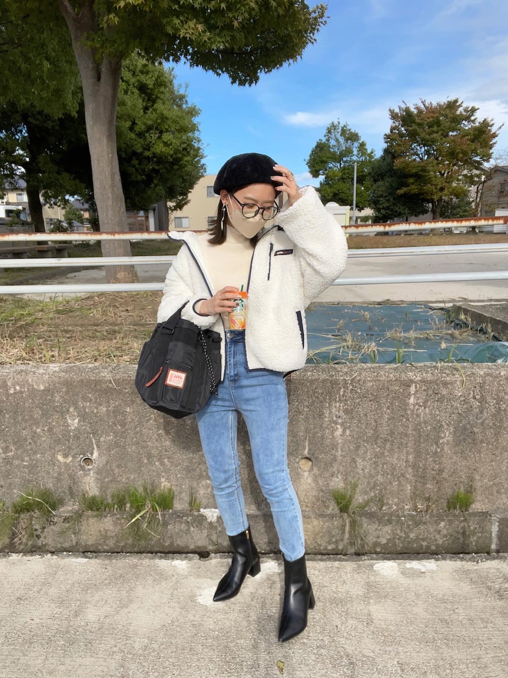 ホワイト系のブルゾン、ホワイト系のニット/セーター、ブラック系のショルダーバッグを着用したレディースの冬コーディネートの3枚目の写真