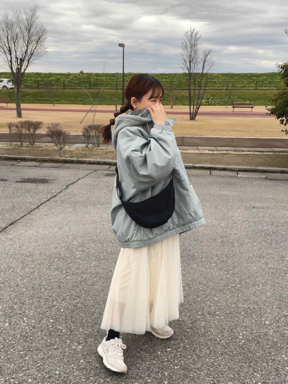 ブルー系のブルゾン、ホワイト系のスカート、ブラック系のショルダーバッグを着用したレディースの冬コーディネートの5枚目の写真