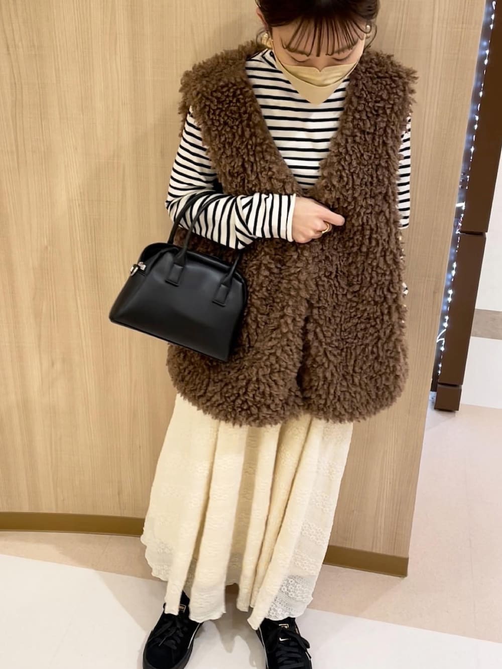 ブラウン系のベスト、ホワイト系のニット/セーター、ベージュ系のスカートを着用したレディースの冬コーディネートの4枚目の写真