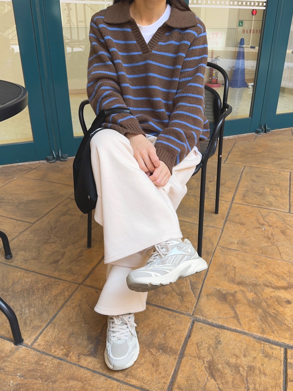 ブラック系のトートバッグ、ブラウン系のニット/セーター、ホワイト系のパンツを着用したレディースの冬コーディネートの2枚目の写真