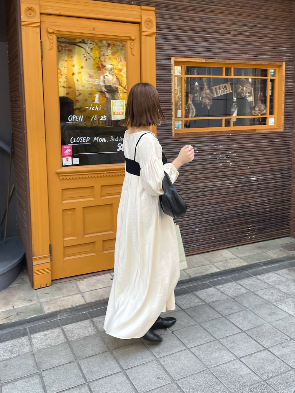 ホワイト系のワンピース、ブラック系のハンドバッグ、ブラック系のブーツを着用したレディースの秋コーディネートの3枚目の写真