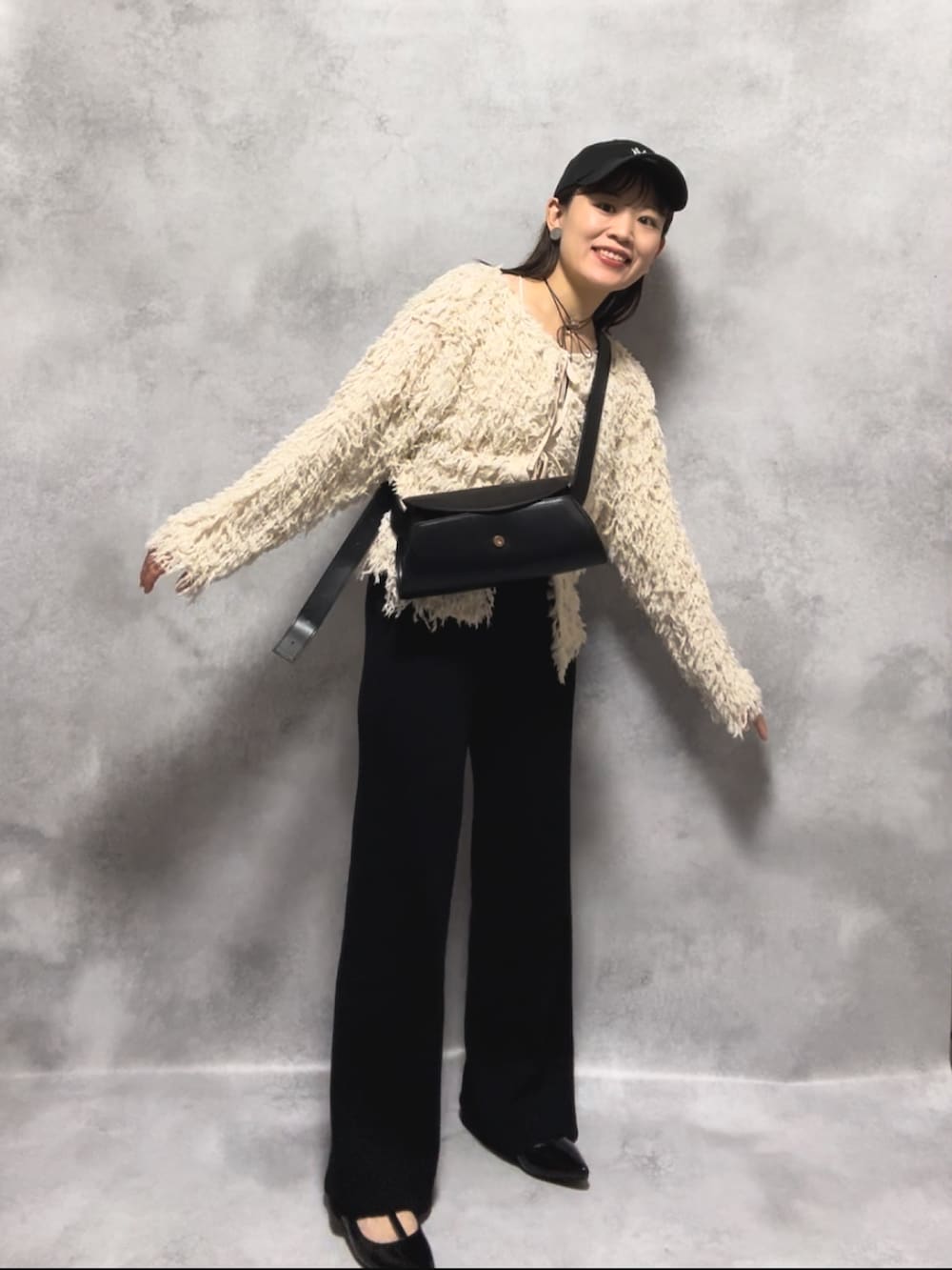 ホワイト系のカーディガン/ボレロ、ブラック系のパンツ、ブラック系のショルダーバッグを着用したレディースの秋コーディネートの3枚目の写真