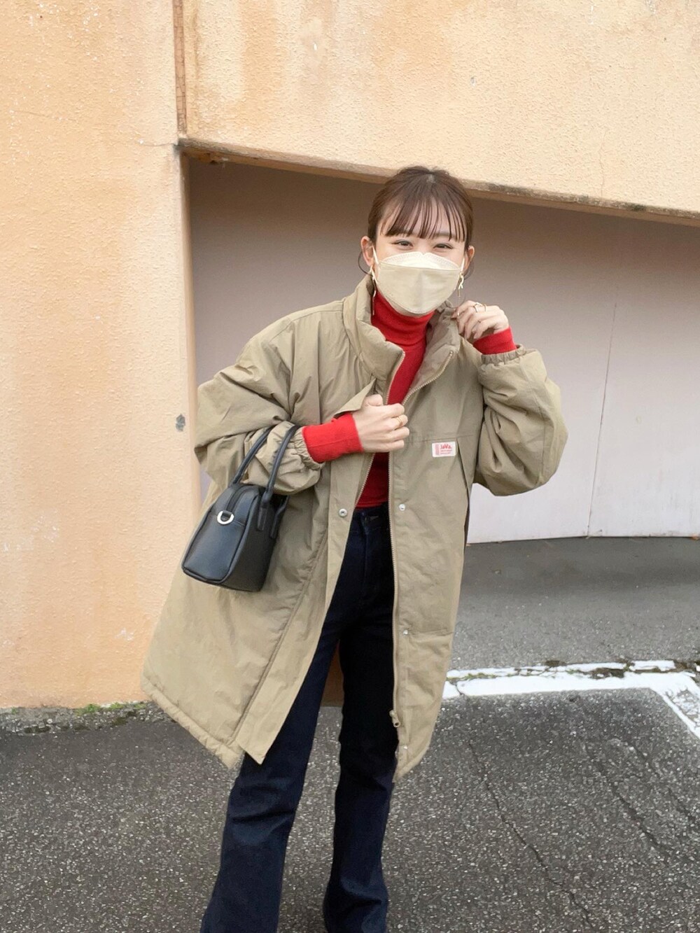 ベージュ系のダウンジャケット/コート、レッド系のトップス、ブルー系のデニムパンツを着用したレディースの冬コーディネートの5枚目の写真