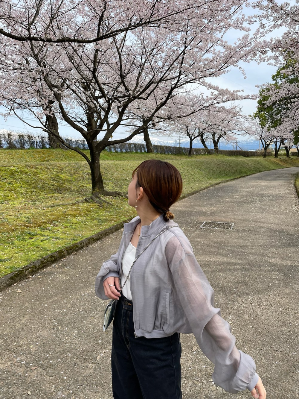 グレー系のブルゾン、ブラック系のデニムパンツ、ホワイト系のシューズを着用したレディースの春コーディネートの5枚目の写真