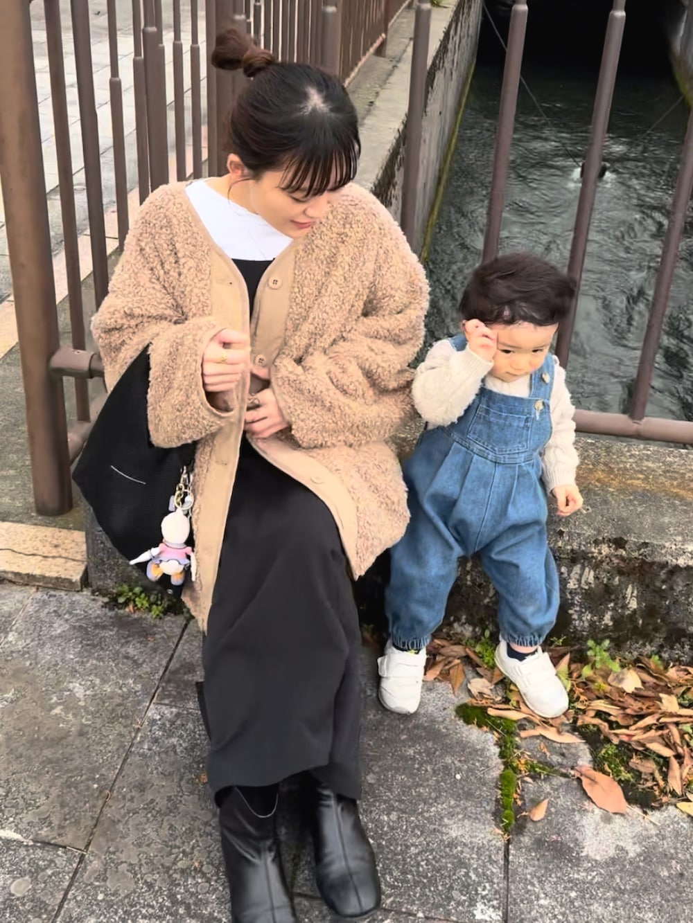 ブラック系のワンピース、ベージュ系のブルゾン、ブラック系のブーツを着用したレディースの冬コーディネートの5枚目の写真