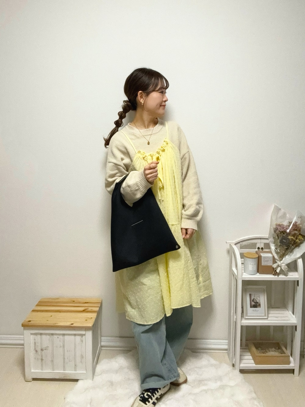 イエロー系のワンピース、ブルー系のデニムパンツ、ベージュ系のスニーカーを着用したレディースの冬コーディネートの3枚目の写真