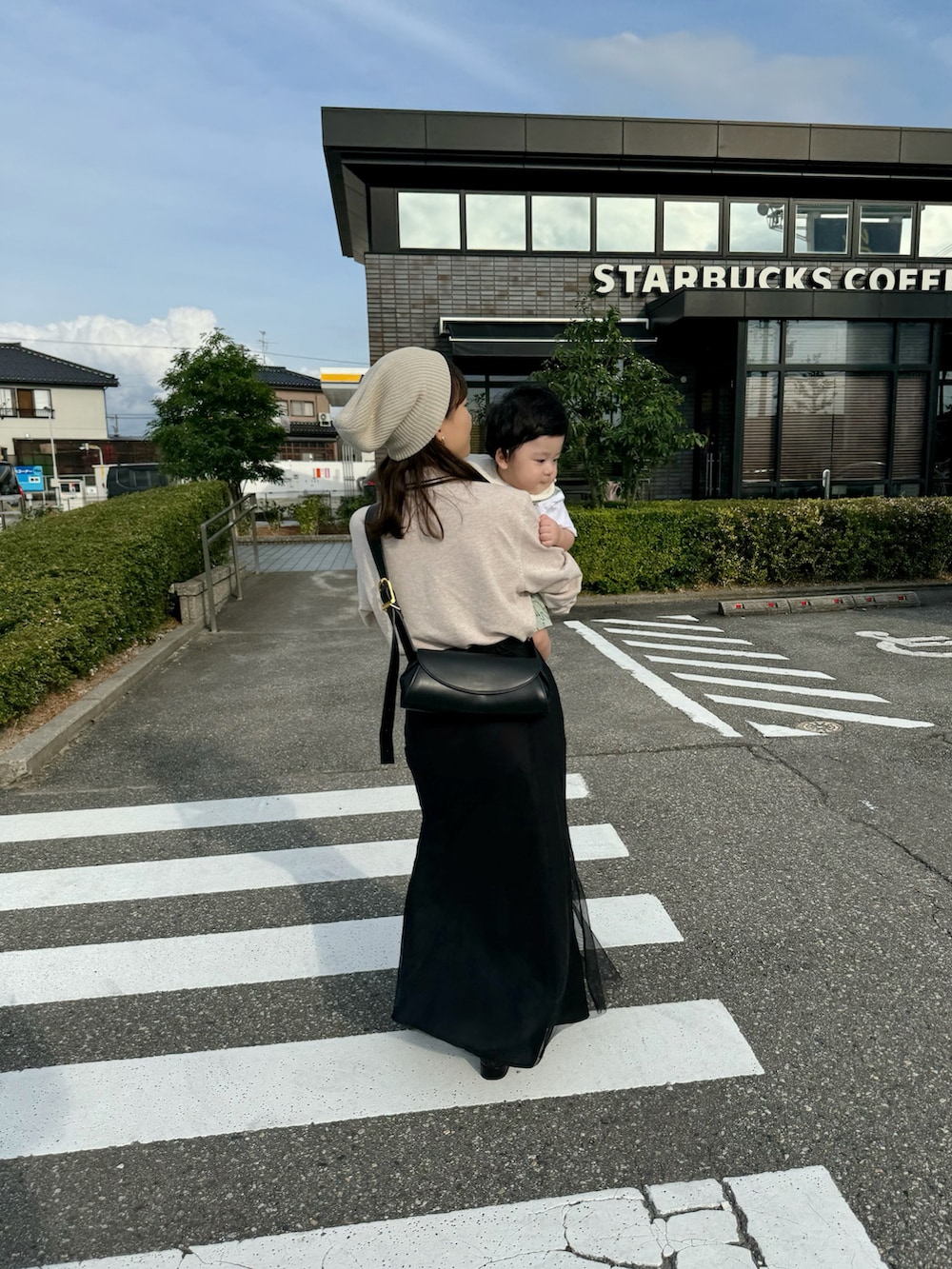 ベージュ系のポロシャツ、ブラック系のスカート、ブラック系のショルダーバッグを着用したレディースの秋コーディネートの3枚目の写真