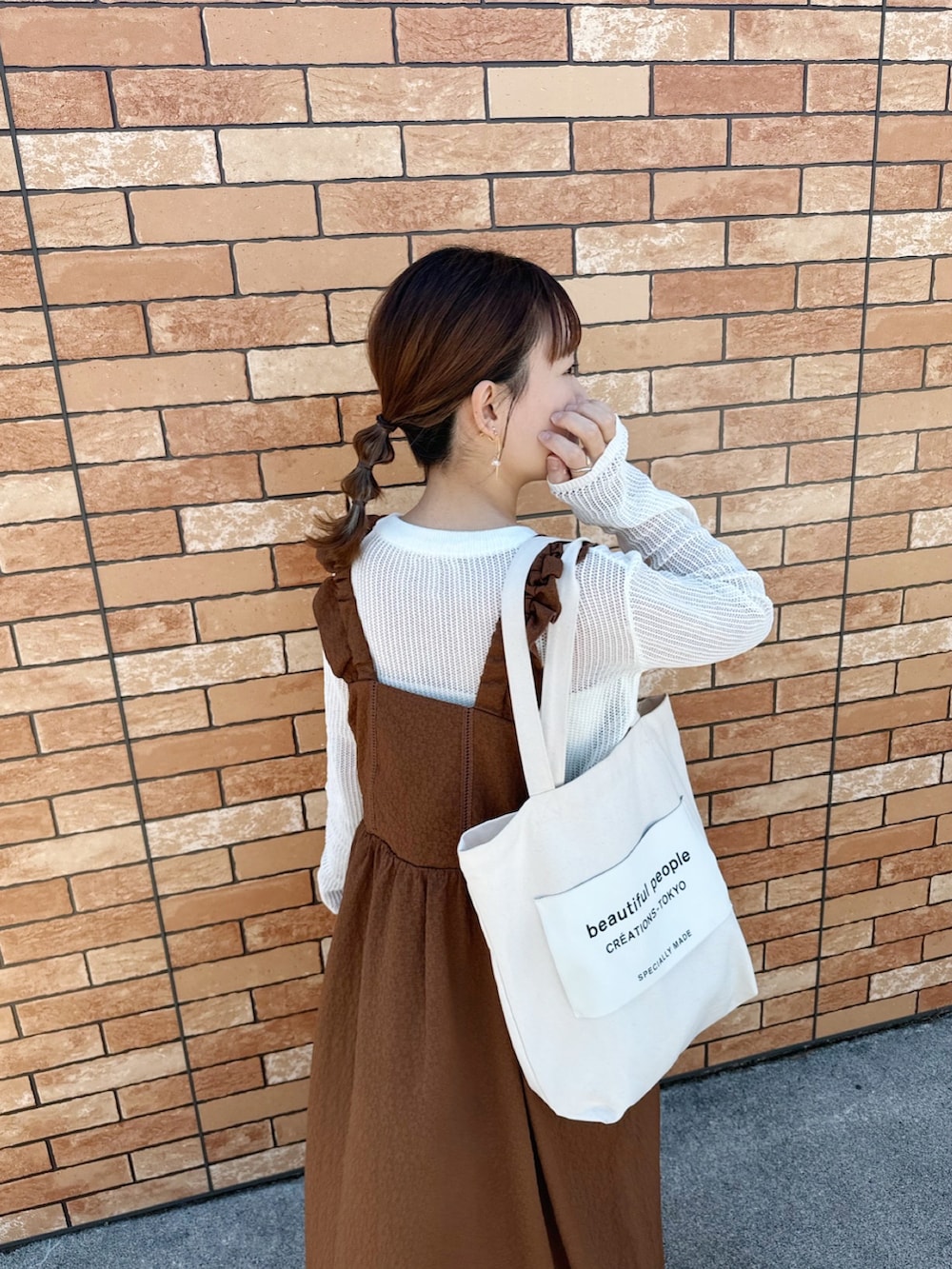 ブラウン系のワンピース、ホワイト系のトップス、ホワイト系のトートバッグを着用したレディースの春コーディネートの2枚目の写真