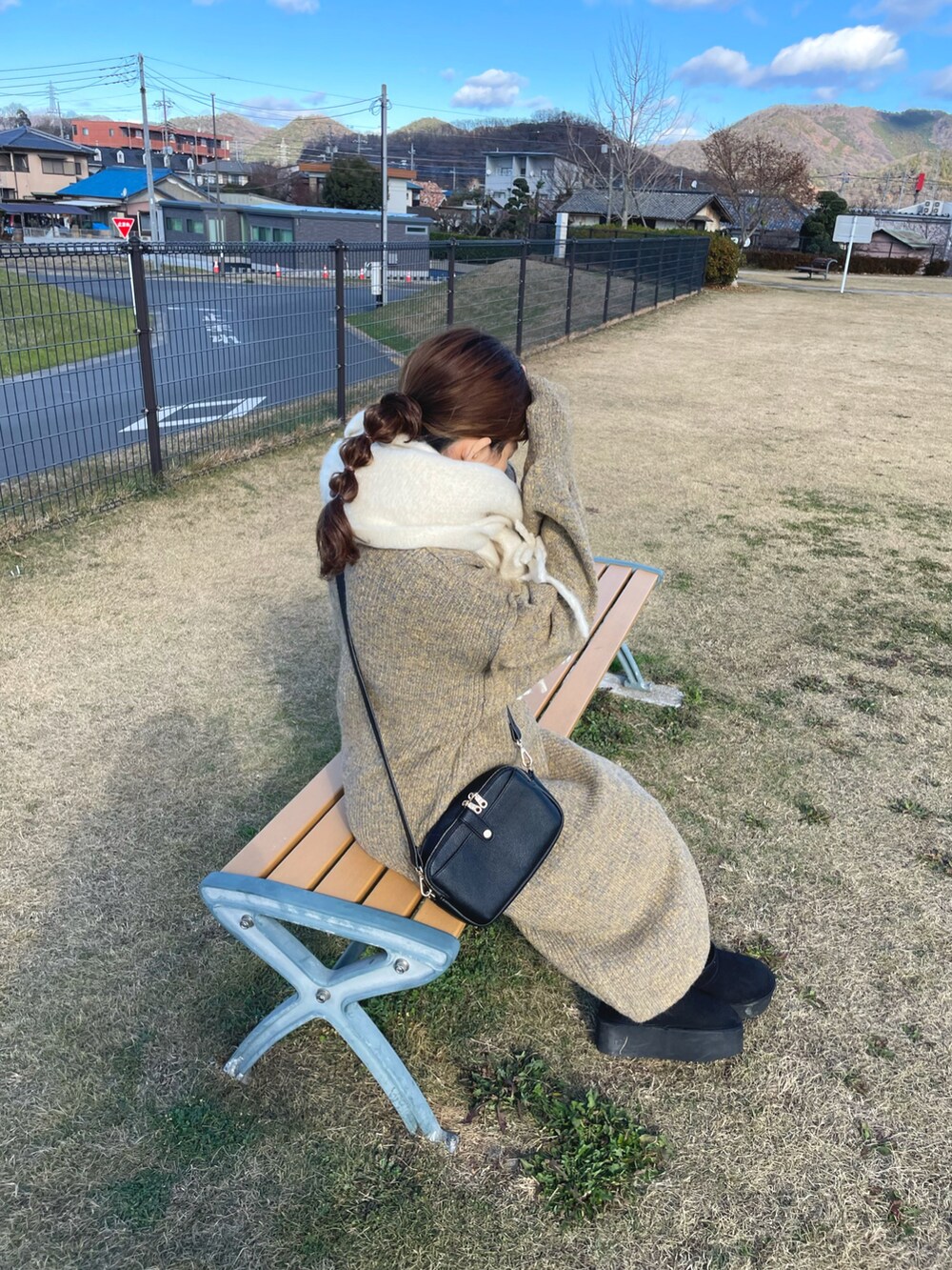 イエロー系のワンピース、ブラック系のショルダーバッグ、ブラック系のブーツを着用したレディースの冬コーディネートの3枚目の写真