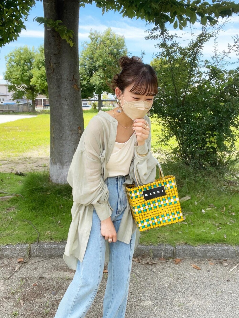 グリーン系のシャツ/ブラウス、ホワイト系のキャミソール、ブルー系のデニムパンツを着用したレディースの夏コーディネートの2枚目の写真