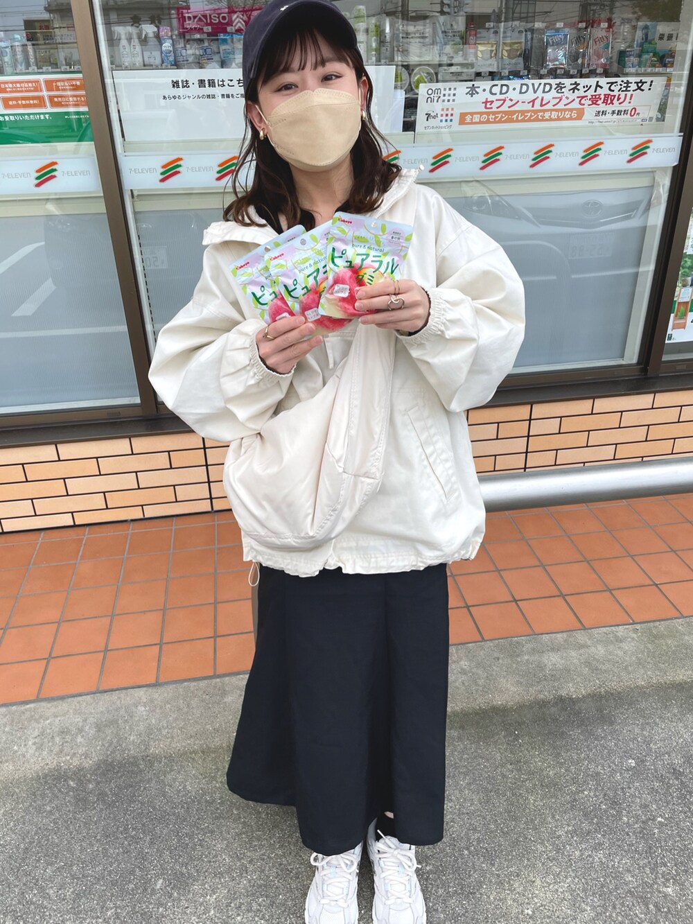 ホワイト系のパーカー、ブラック系のジャンパースカート、オレンジ系のキャミソールを着用したレディースの春コーディネートの4枚目の写真