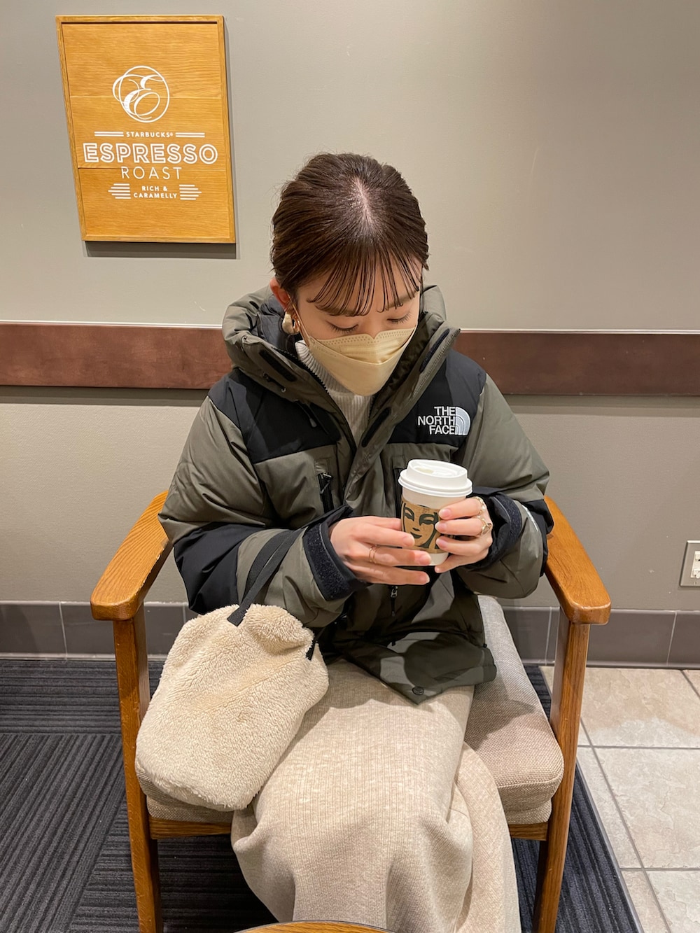 グリーン系のダウンジャケット/コート、ホワイト系のニット/セーター、ベージュ系のスカートを着用したレディースの冬コーディネートの4枚目の写真