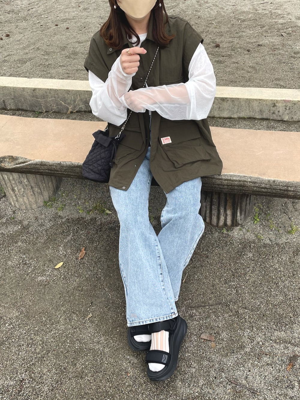 グリーン系のマウンテンパーカー、ホワイト系のTシャツ/カットソー、ブルー系のデニムパンツを着用したレディースの春コーディネートの3枚目の写真