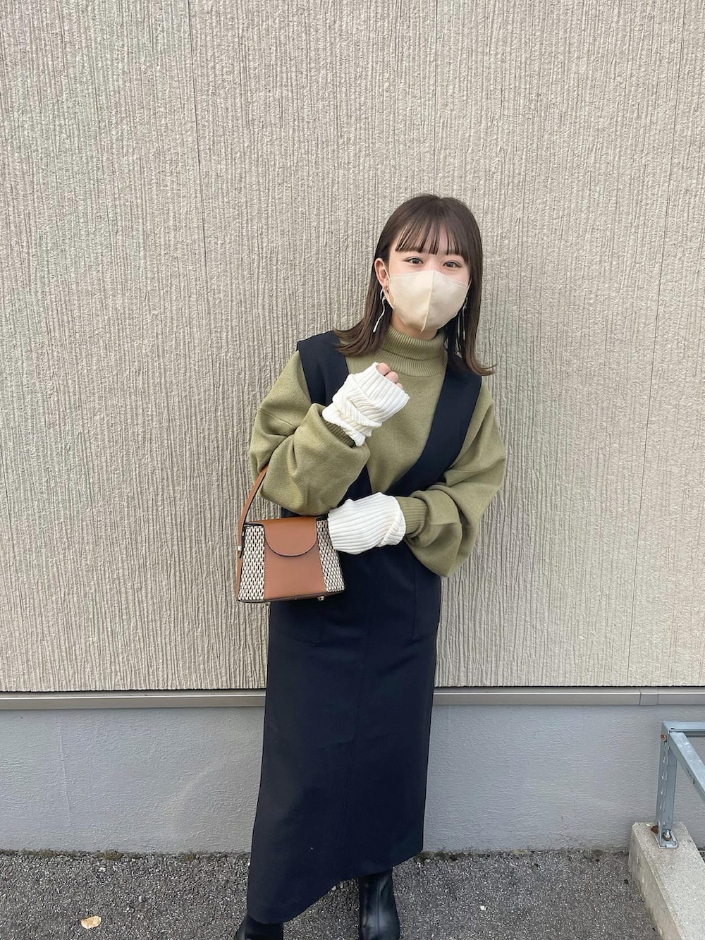 ブラック系のジャンパースカート、グリーン系のニット/セーター、イエロー系のショルダーバッグを着用したレディースの秋コーディネートの3枚目の写真