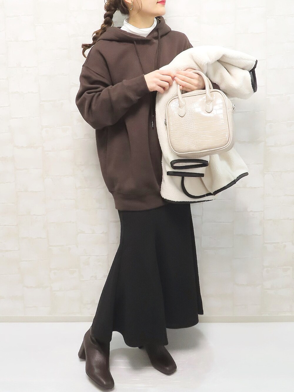 ブラウン系のパーカー、ブラック系のスカート、ホワイト系のその他アウターを着用したレディースの冬コーディネートの2枚目の写真