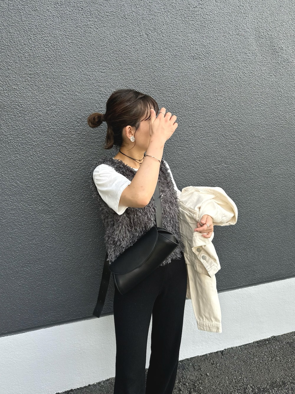 グレー系のベスト、ブラック系のパンツ、ホワイト系のデニムジャケットを着用したレディースの秋コーディネートの5枚目の写真