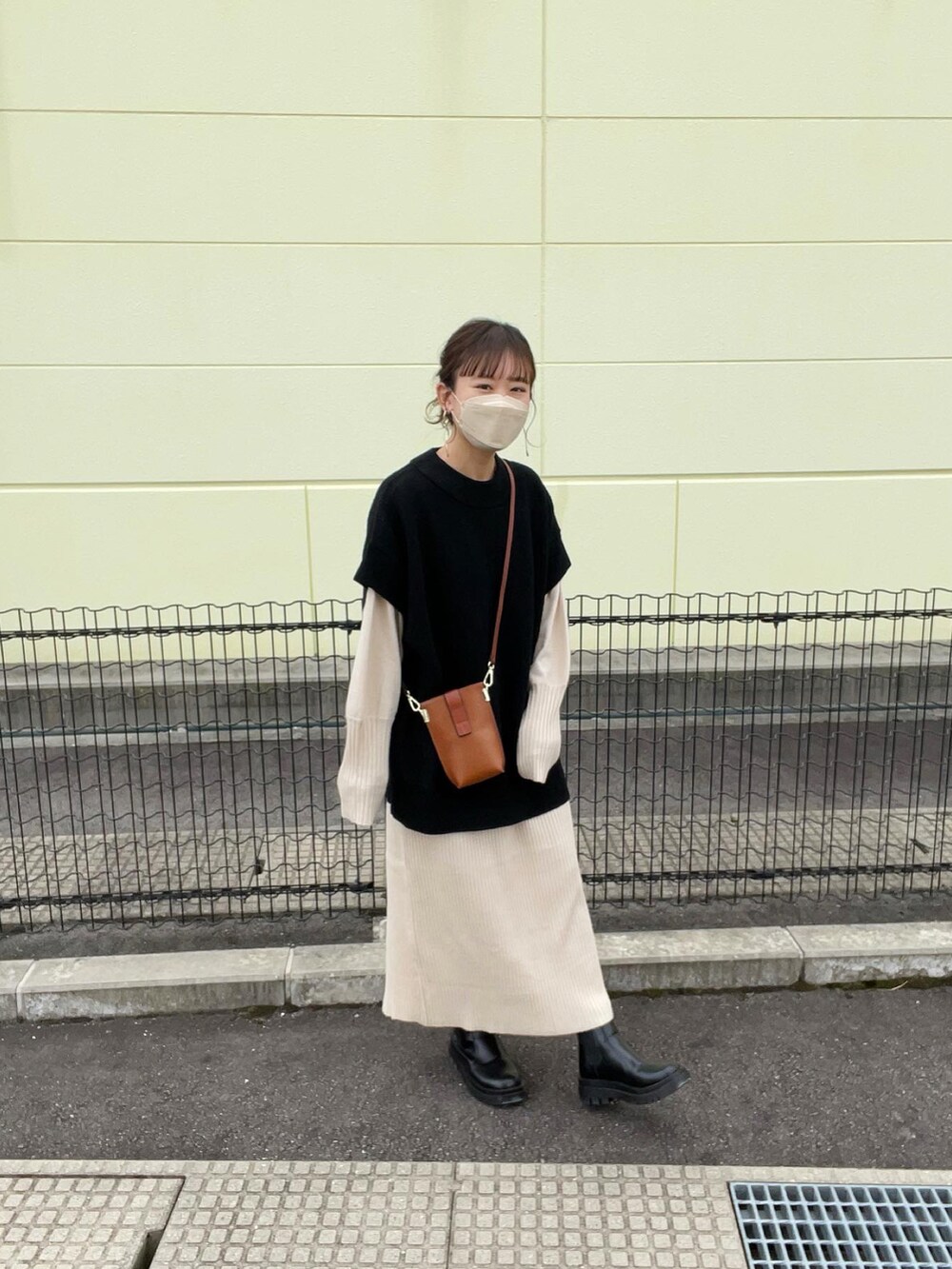 ブラック系のベスト、ホワイト系のワンピース、ブラウン系のショルダーバッグを着用したレディースの秋コーディネートの5枚目の写真