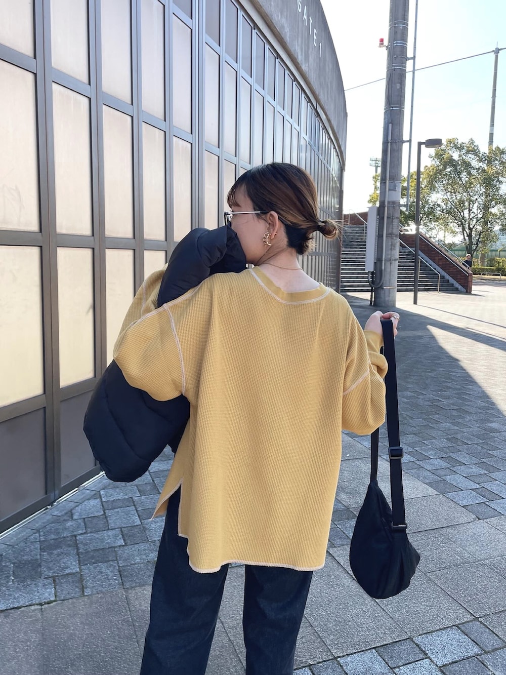 ブラック系のダウンベスト、イエロー系のTシャツ/カットソー、ブラック系のデニムパンツを着用したレディースの冬コーディネートの3枚目の写真