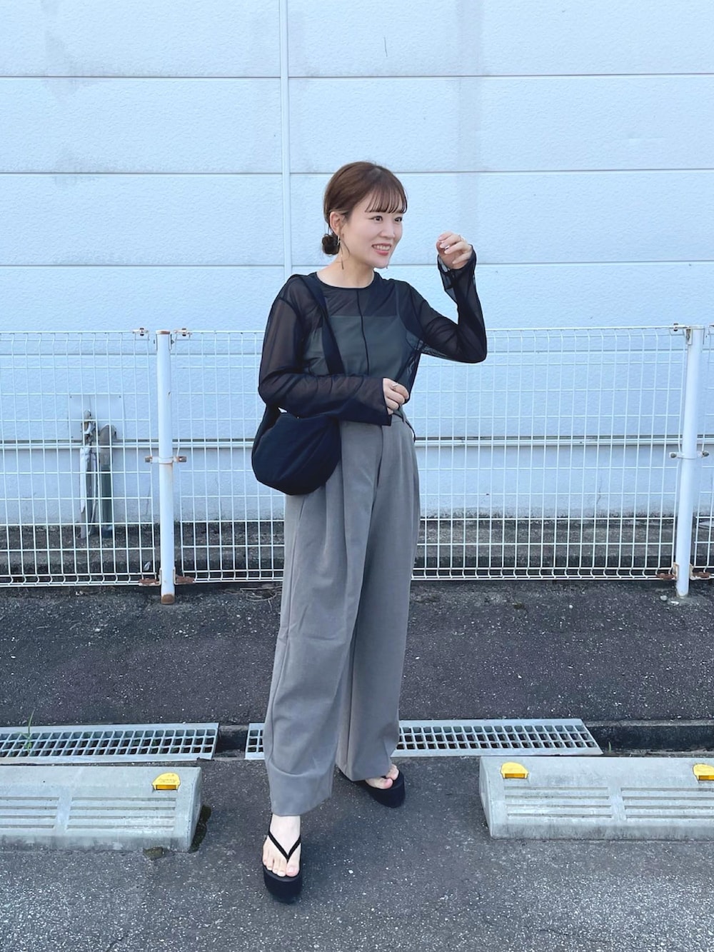 ブラック系のトップス、ブラウン系のパンツ、ブラック系のショルダーバッグを着用したレディースの夏コーディネートの3枚目の写真