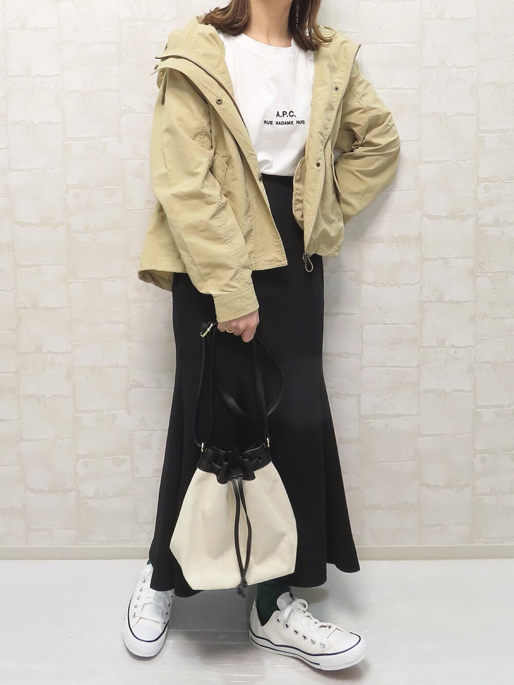 ベージュ系のマウンテンパーカー、ホワイト系のニット/セーター、ブラック系のスカートを着用したレディースの冬コーディネートの3枚目の写真