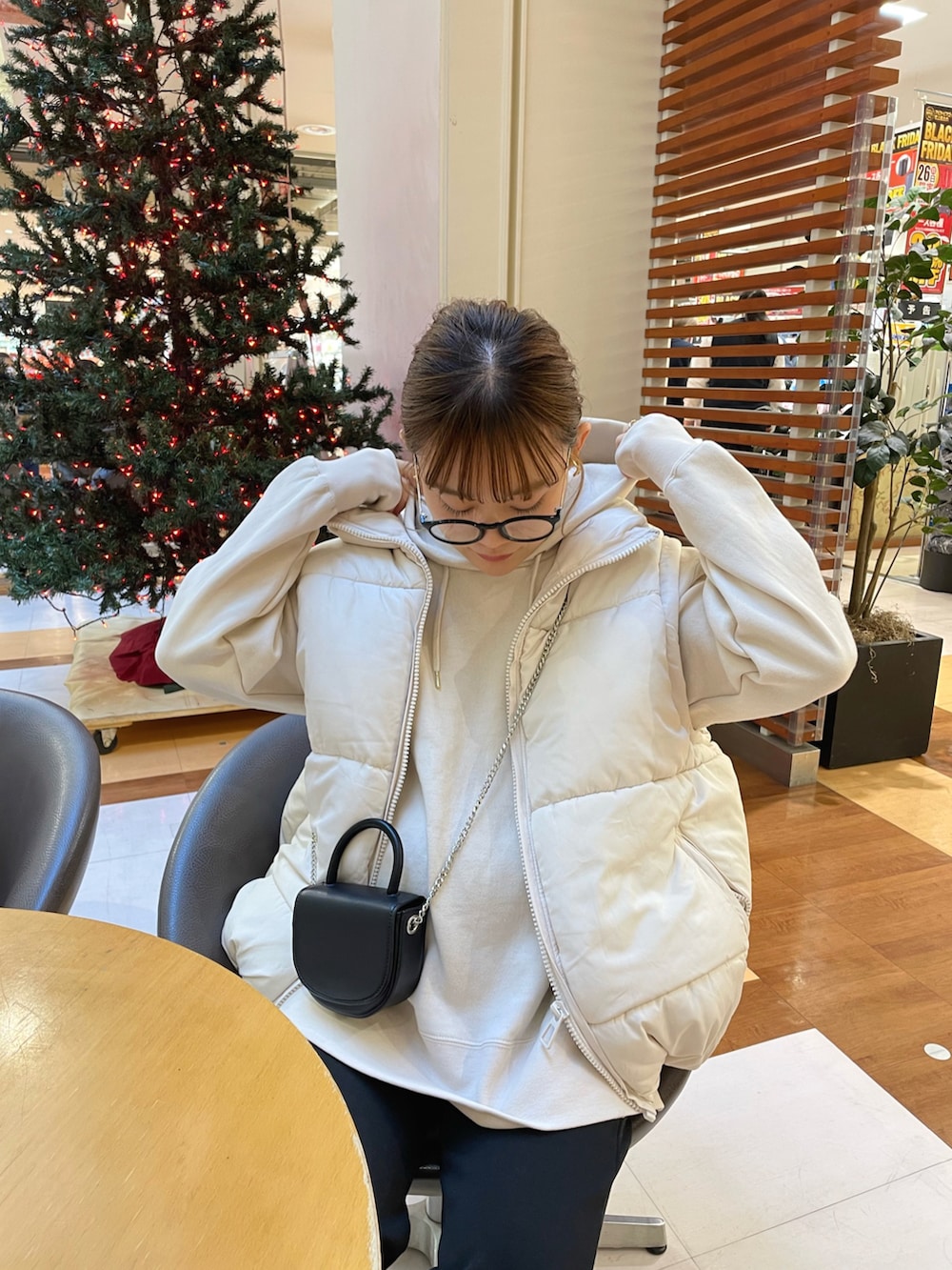 ホワイト系のパーカー、ホワイト系のベスト、ブラック系のショルダーバッグを着用したレディースの冬コーディネートの3枚目の写真