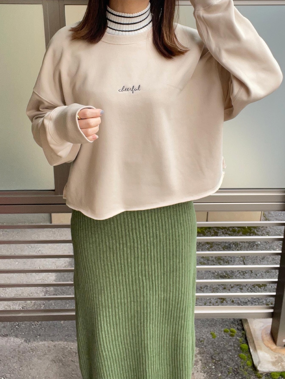 ベージュ系のスウェット、グリーン系のスカート、ホワイト系のニット/セーターを着用したレディースの冬コーディネートの3枚目の写真