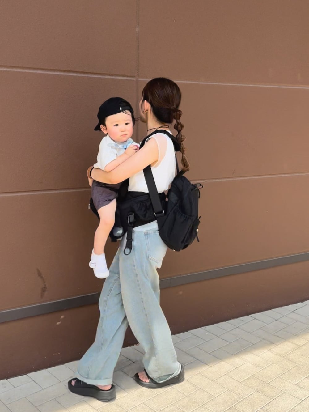 ホワイト系のトップス、ブルー系のデニムパンツ、ブラック系のサンダルを着用したレディースの夏コーディネートの5枚目の写真