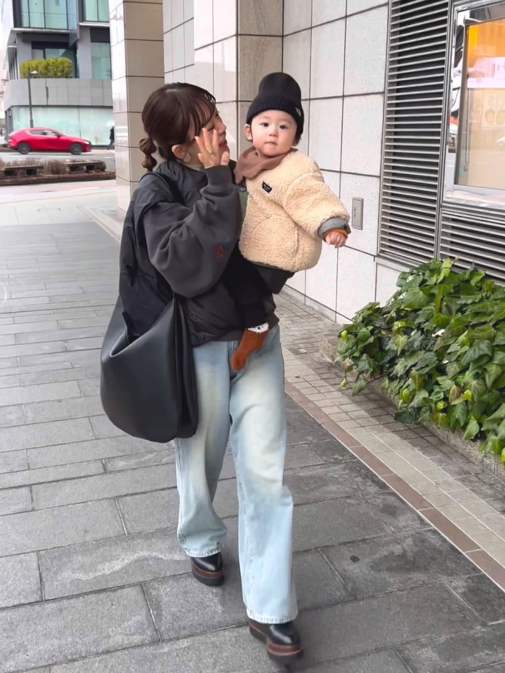 グレー系のスウェット、ホワイト系のニット/セーター、ブルー系のデニムパンツを着用したレディースの冬コーディネートの3枚目の写真