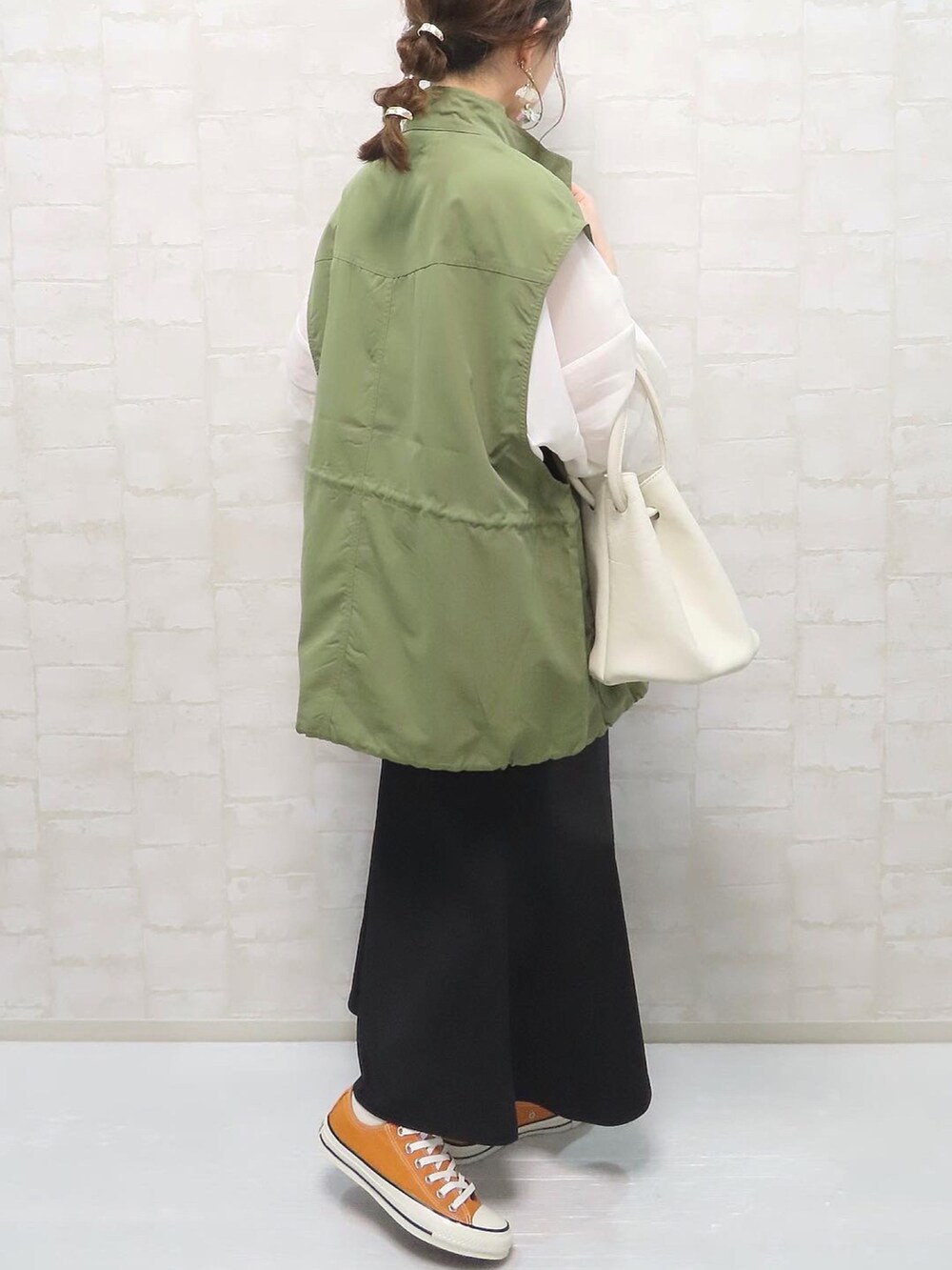 ホワイト系のシャツ/ブラウス、グリーン系のベスト、ホワイト系のハンドバッグを着用したレディースの春コーディネートの2枚目の写真